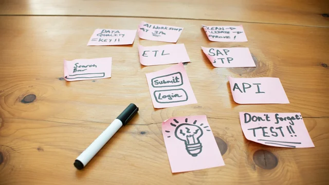 Lističi s koraki procesa, kot so ETL, API in SAP, na leseni mizi
