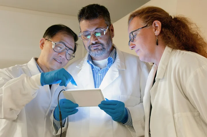 Researchers in a lab reviewing results on a tablet
